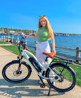 a woman with a black helmet is smiling a citypro ebike in white