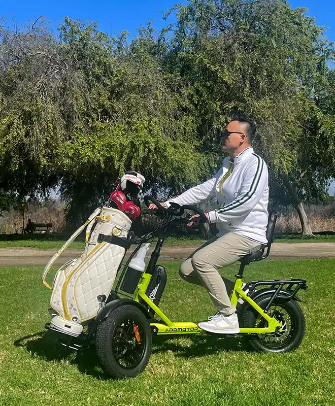 an adult is riding a reverse trike with golf bag on the grass