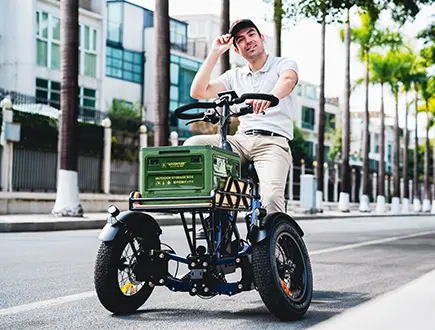 A man is riding Spytan X electric trike with cargo on the street