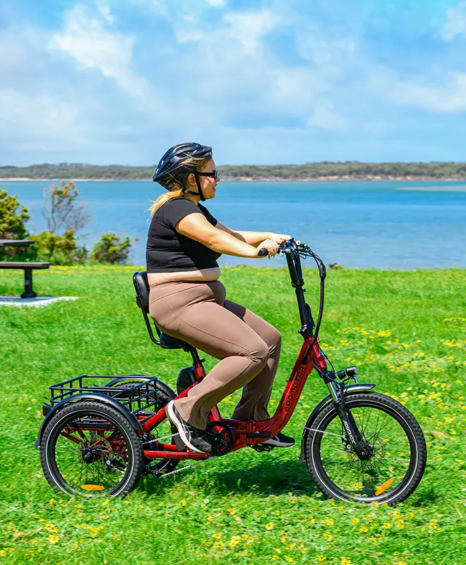 A fat woman is-riding her folding trike on the grass