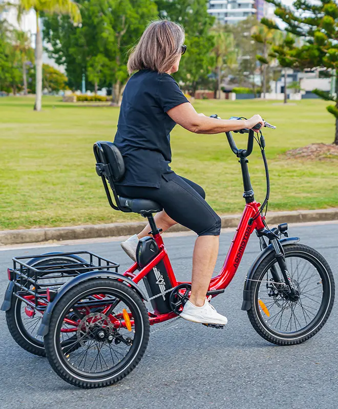 a female senior is ring the citytri trike on the road