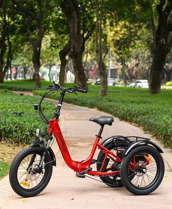 a red citytan folding trike is on a paved trail in the park with a lot of trees