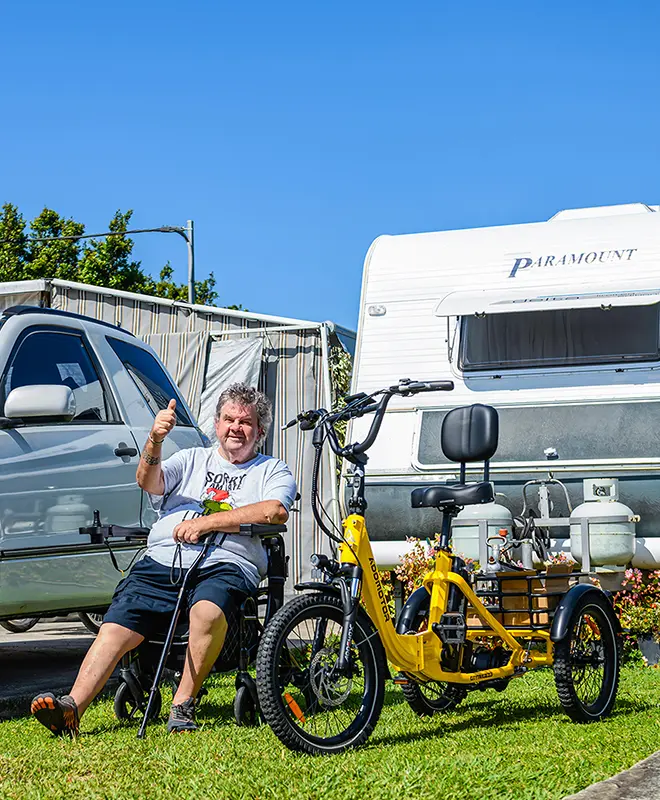 A senior is sitting next to his fodable electric trike