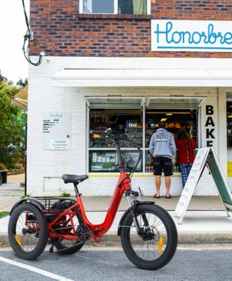 A red Citytan electric trike is parked on the street in front of a store